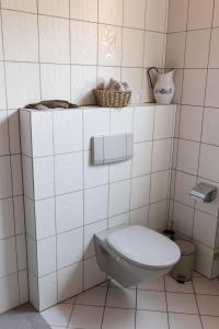 a bathroom with a toilet in a white tiled wall at Haus Jakob in Longkamp