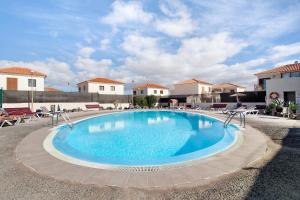 a large swimming pool with chairs and a building at Villa Charlotte in La Oliva