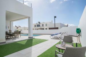 a patio with chairs and a table and a pool at Casa Dubh Linn in Playa Blanca