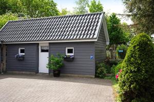 a gray garage with two windows and two doors at Ferienwohnung Tüchsen in Klixbüll