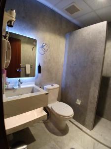 ein Badezimmer mit Toilette, Waschbecken und Spiegel in der Unterkunft Crown Town Hotel in Dschidda