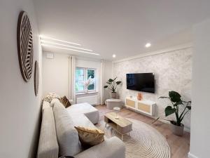 a living room with a white couch and a tv at Casa Kokorey in Rellingen