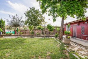 a yard with a red house and trees at Cal Jaume in Masquefa