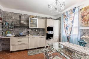 a kitchen with white cabinets and a glass table at Le Case di Erminia Vintage Valeggio in Valeggio sul Mincio +15 photos