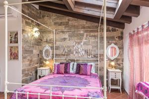 a bedroom with a pink bed and a stone wall at Le Case di Erminia Vintage Valeggio in Valeggio sul Mincio