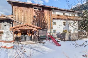 a house with a playground in the snow at Ferienhaus Wechner in Häselgehr