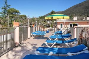 a row of blue and white chairs and an umbrella at Monolocale La Pineta 46 in Albenga