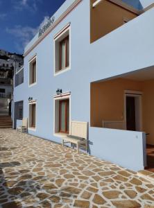 a white building with a bench on a stone floor at Anemi Leros Apartments 3 in Panteli