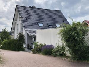a white house with a black roof and a brick driveway at Ferienwohnung Bäumchenblick in Müllheim