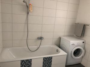 a bathroom with a tub and a washing machine at Ferienwohnung Bäumchenblick in Müllheim