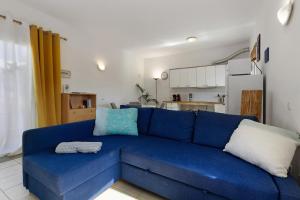 a blue couch in a living room with a kitchen at La Finca Las Estrellas in Tarajalejo