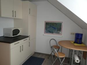 a kitchen with white cabinets and a table and a microwave at Ferienwohnung Zerlaut in Langenargen +15 photos