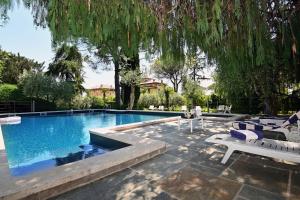 a swimming pool with lounge chairs and a tree at Al Segnavento Fasanella in Toscolano Maderno +21 photos