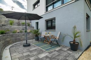a patio with a table and an umbrella at Ferienwohnung mit eigenem Eingang in Deggenhausertal