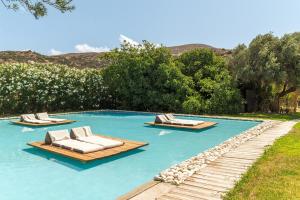 two lounges and lounge chairs in a swimming pool at Ow Andros Suite 2,Private Whirlpool in Andros