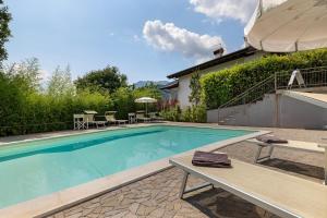 a swimming pool with a bench next to a house at Eco del Garda Apartments in Tenno