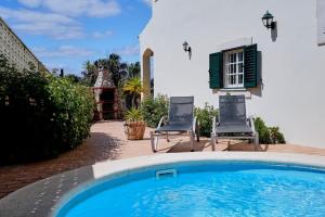 a swimming pool with two chairs and a house at Sunset Villa in Ferragudo