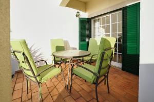 a dining room with green chairs and a table at Sunset Villa in Ferragudo