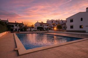 a swimming pool in the middle of a courtyard with houses at Binimar - Cala en Porter in Cala en Porter