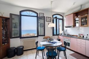 a kitchen with a table and some chairs and some windows at Wonderful flat by sea chez Monique in Bordighera