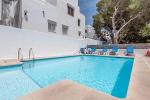 a swimming pool with blue chairs and a building at Apartamentos Karin 2ºd in Cala d´Or