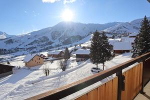 a village covered in snow with the sun in the background at Le Col Panoramic in La Toussuire