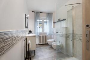 a bathroom with a toilet and a glass shower at Sweet Home Apartments Bambù in Arona +19 photos