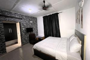 a bedroom with a white bed and a brick wall at Elite Hotel in Ekpoma