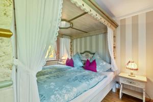 a bedroom with a canopy bed with pink and blue pillows at Tannenhäuschen Sauerland in Schmallenberg +30 photos
