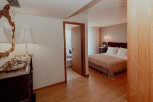 a hotel room with a bed and a mirror at Fonte do Pinheiro Boutique in Ponte de Lima
