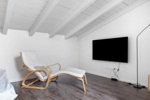 a white room with a chair and a tv at Appartamento Castello a Raffa in Puegnago