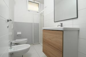 a bathroom with a sink and a toilet and a mirror at Cormorani - Appartamento 8 in Golfo Aranci +20 photos