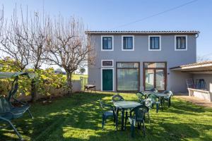 a yard with tables and chairs in front of a house at Casa La Calleja in Arzúa