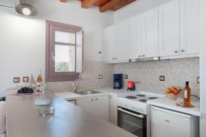 a white kitchen with white cabinets and a sink at Nicolas House 1 in Rakhídhion