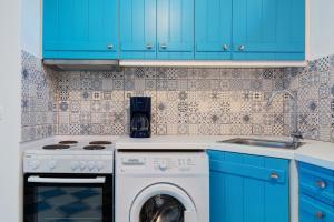 a kitchen with blue cabinets and a washing machine at Nicolas House 3 in Rakhídhion
