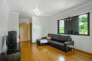 a living room with a black leather couch and a window at Apartamento Eden in Machico