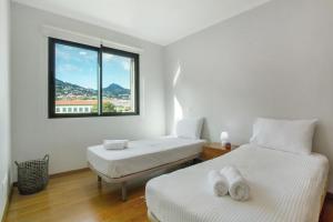 two beds in a white room with a window at Apartamento Eden in Machico