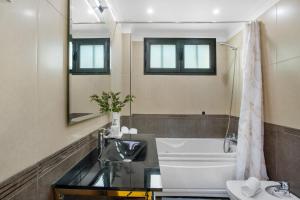 a bathroom with a sink and a tub and a mirror at Apartamento Eden in Machico +18 photos