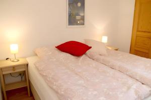 a white bed with a red pillow on top of it at Ferienwohnung Jachmann, 80qm in Schönwald