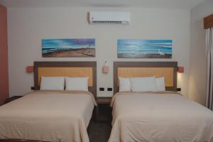 two beds in a hotel room with two beds at Hotel Calma Celesti in Perihuete