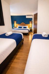 a bedroom with two beds with blue walls and wooden floors at The Originals City, Hôtel Mâcon Sud in Chaintré