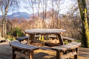 a wooden picnic table and benches on a wooden deck at An Bothan in Isleornsay