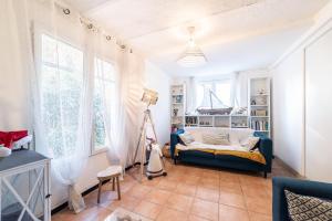 a living room with a blue couch and windows at Maison type Canetoise prox plage in Canet-en-Roussillon
