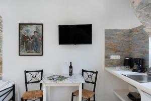 a kitchen with a table and a television on a wall at Politimis Studio N6 in Amorgos