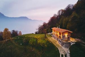 a house on top of a hill with lights on at Bellagio - Baita treeb Tramontana in Bellagio