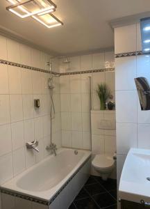 a bathroom with a tub and a toilet and a sink at Gemütliche Wohnung in Ortsrandlage in Rüdesheim am Rhein +37 photos