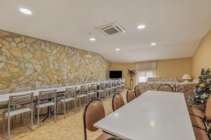 a conference room with tables and chairs and a stone wall at El Ático in Maluenda