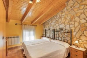 a bedroom with a bed and a stone wall at El Ático in Maluenda