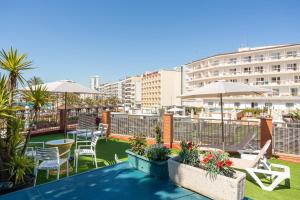 a balcony with chairs and tables and umbrellas at S23 Sa Caleta in Lloret de Mar