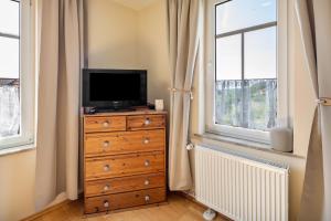 a television on a dresser in a room with windows at Bachmanns Ferienwohnung 2 in Schotten